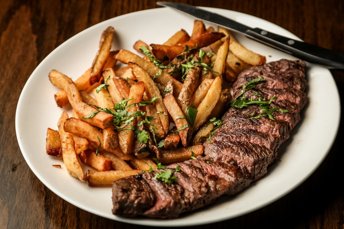 Steak frites servi en bistrot, lumière chaude